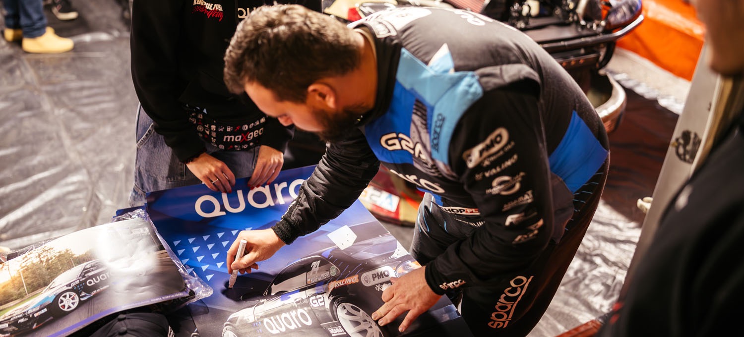 Driver signing posters for fans in the Drift Masters paddock