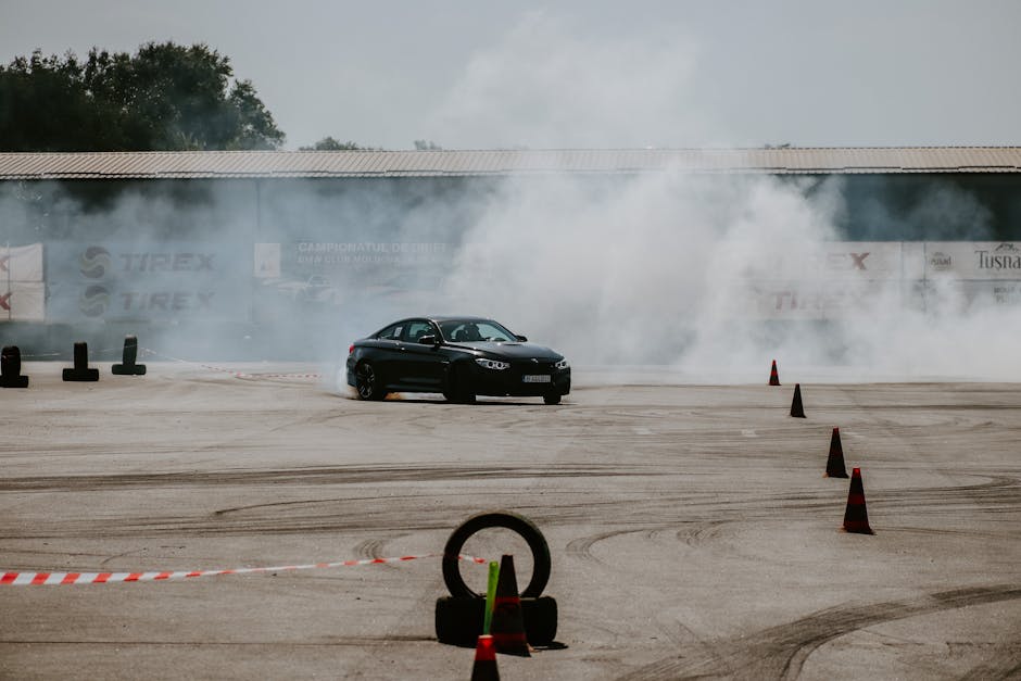 Czarne auto w drifcie z kłębami dymu na torze z pachołkami